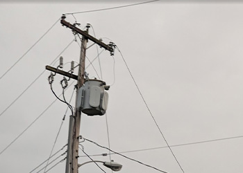 Utility pole with transformer and loose wires.